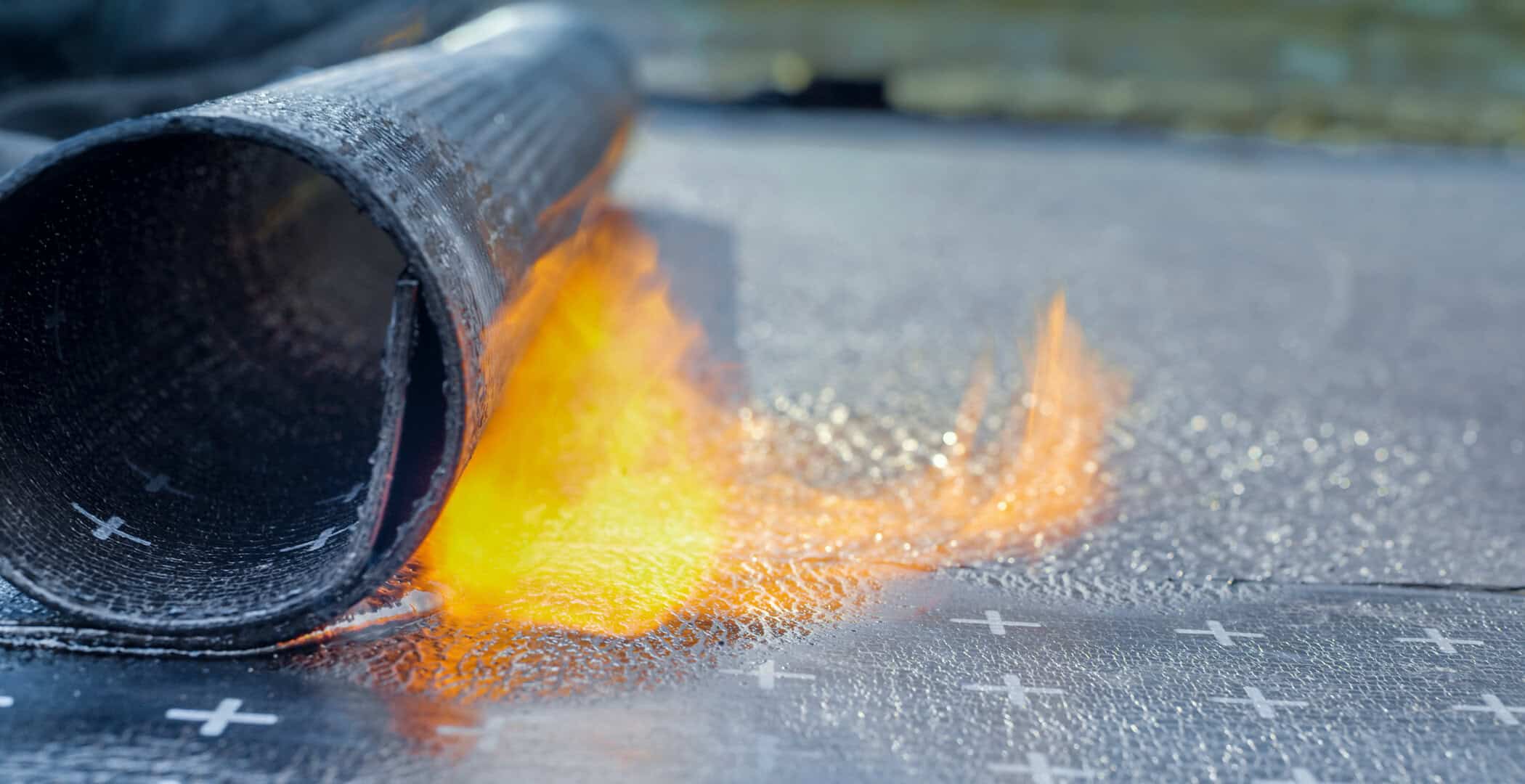 Flamer from a torch heat roofing tag during an installation of roofing material on a commercial building.