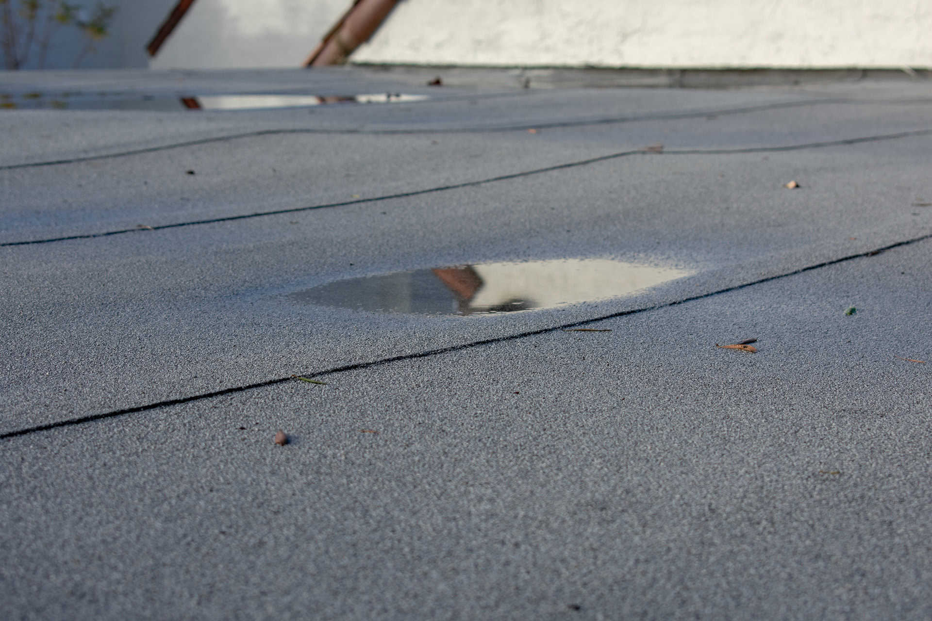 Water puddles on a flat roof in need of emergency service.