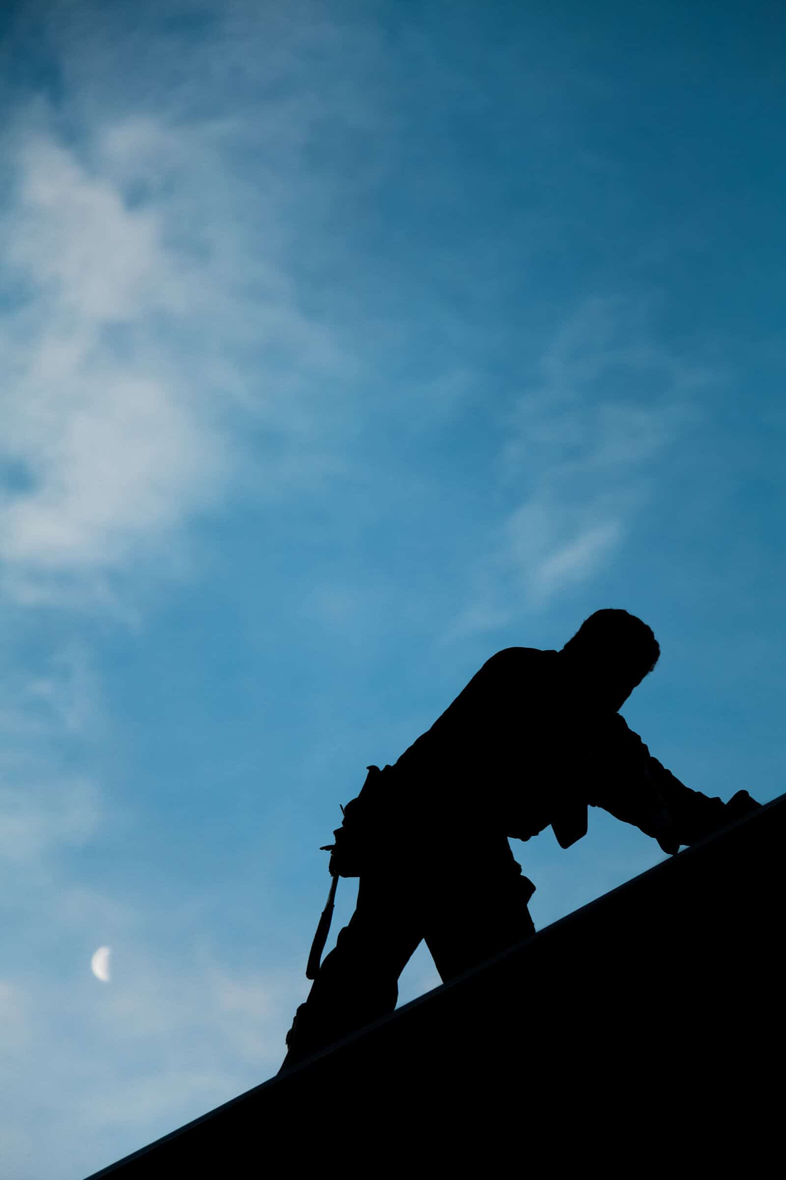 Commercial roofer installs new roof with a blue sky in the background.